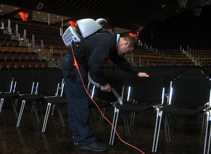 Reinigungskraft mit Rückensauger in der Halle Münsterland